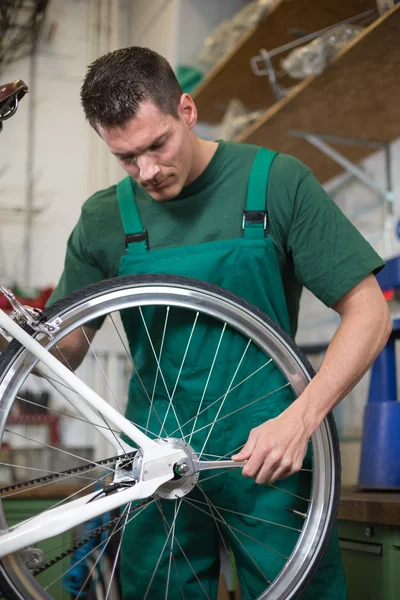 Mechanic repairing wheel on a bicycle in workshop