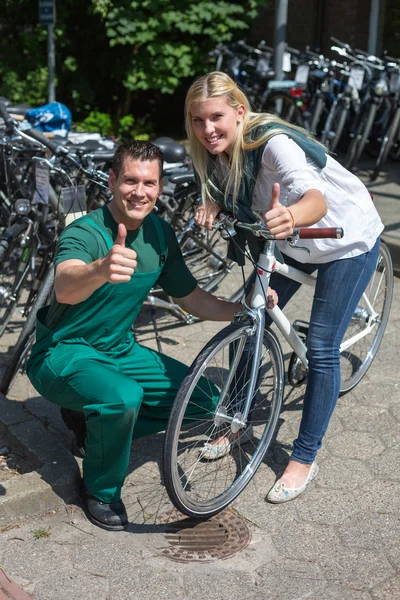 Bicycle mechanic and customer in bike store giving thumbs up