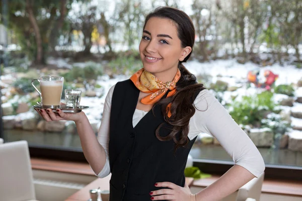 Waitress posing with cup of coffee in cafe or restaurant