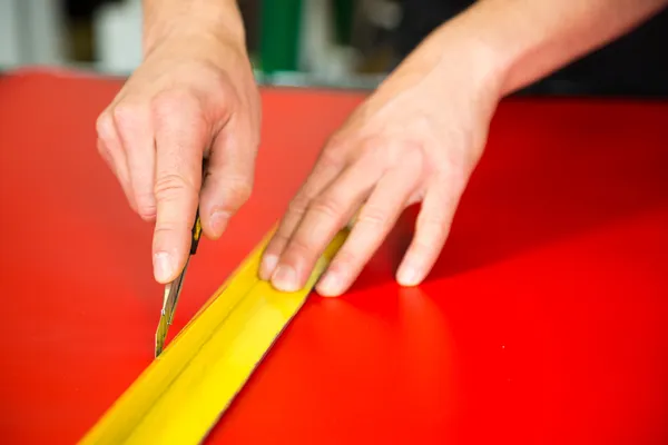 Car wrapping specialist cutting foils with box cutter