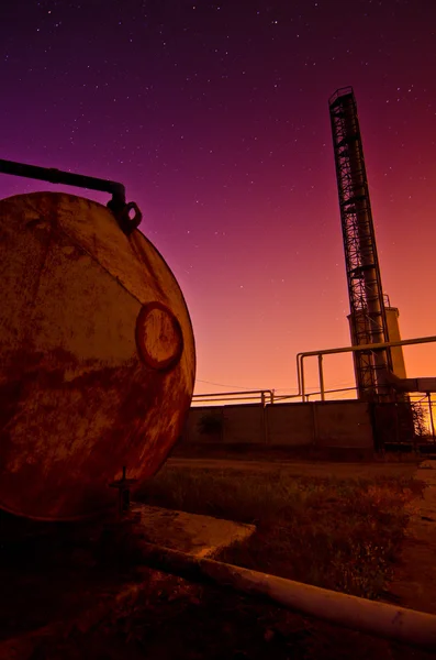 Colourful sunset behind an industrial crane and tank