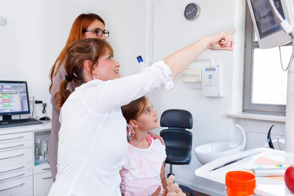 A doctor showing a young family a X-ray picture on LED monitor