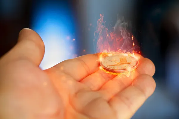 Hand with dollar coin in fire