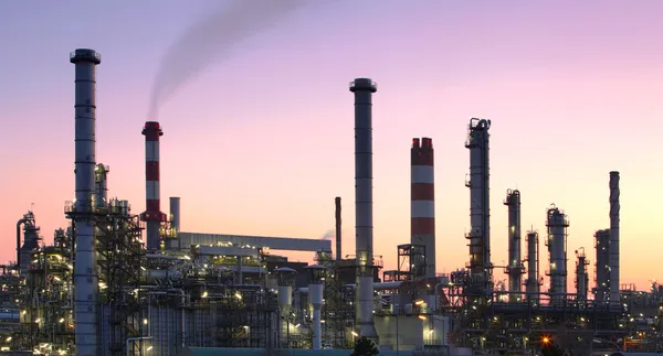 Oil refinery factory silhouette over sunset