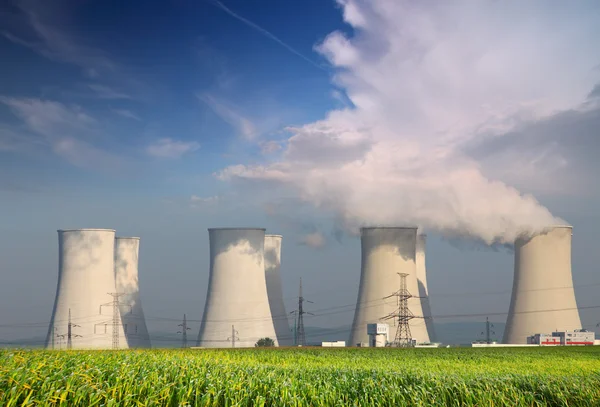 Nuclear power plant with yellow field and big blue clouds.