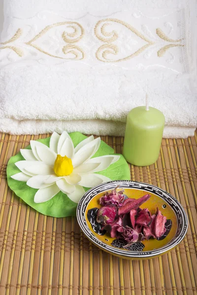 Spa and wellness setting with natural rosebuds, candle and towel.