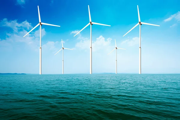 White wind turbine generating electricity on sea