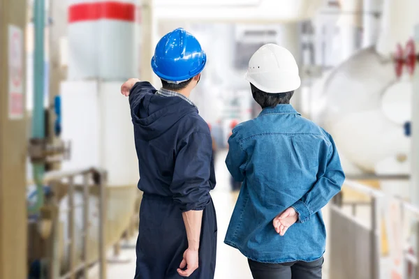 A team of construction workers with helmets at work place in a factory