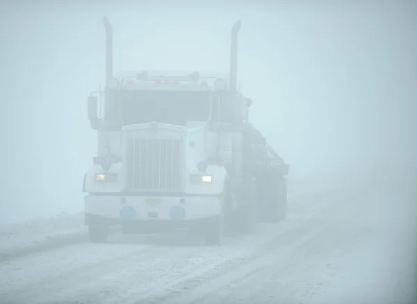White eighteen wheeler truck in snow blizzard, Alaska, US