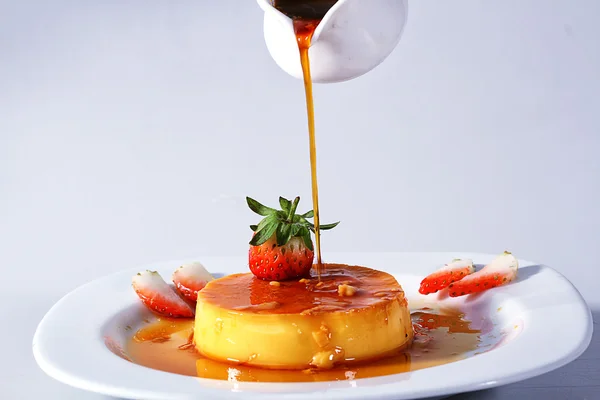 Pouring caramel on lemon pudding - white back ground