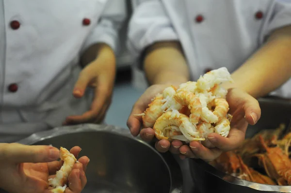 Some fresh shrimps handled by two chefs in a commercial kitchen