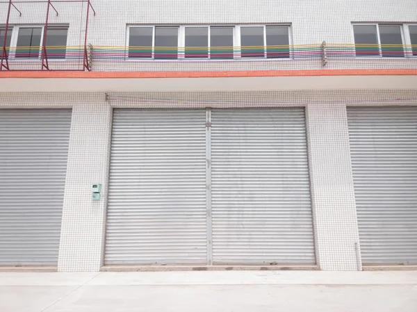 Blank metal shutter doors on commercial shop front, symmetrical