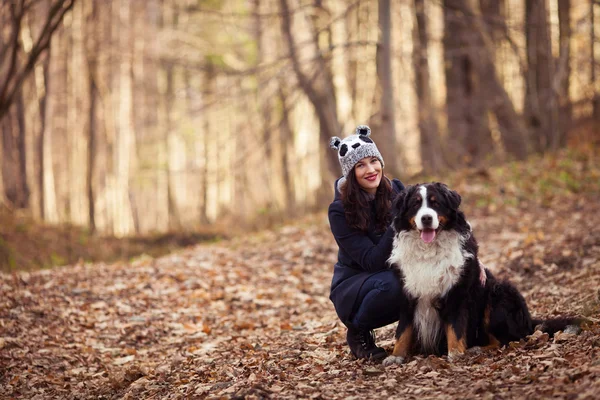 Beautiful Girl with her dog in autumn forest. Bernese Dog