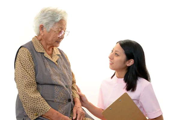 Friendly nurse cares for an elderly woman