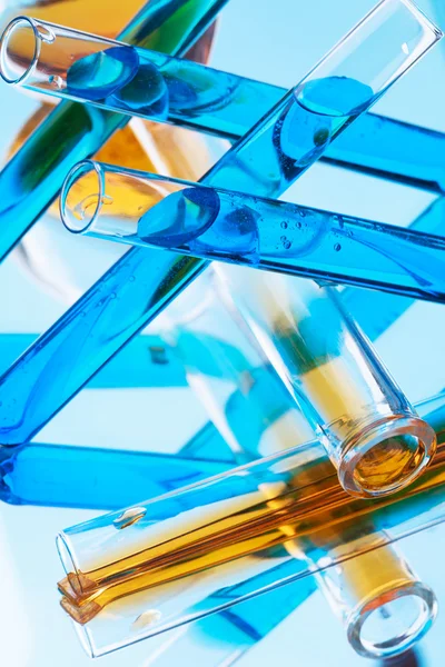 Test tubes with colored liquid (yellow and blue) on light blue b