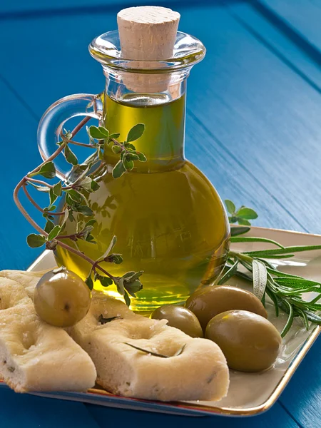 A bottle of olive oil with olives and herbs