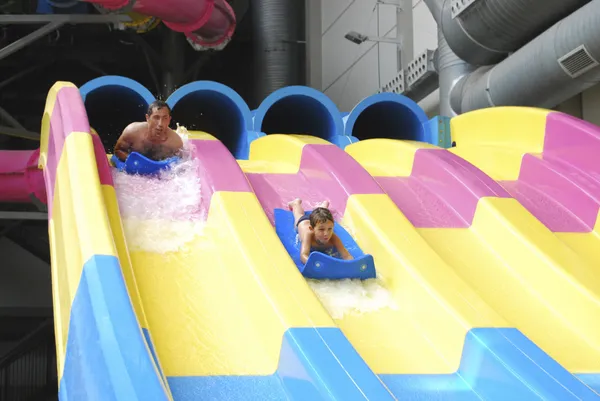 Father and son riding in the water park with slides.