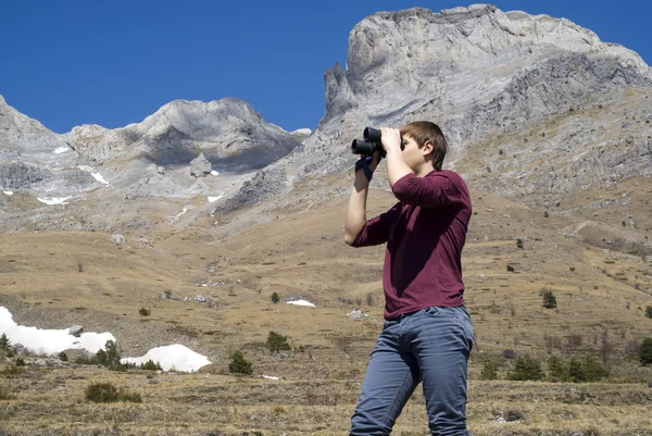 Mountain hiker looking through binoculars