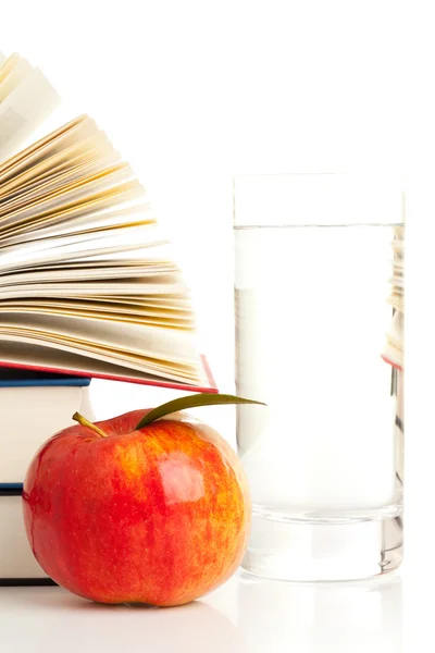 Books with apple and glass of water