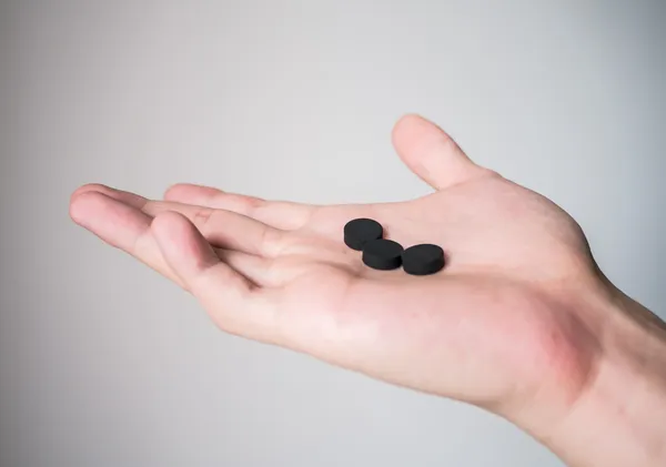 Hand holding black pills