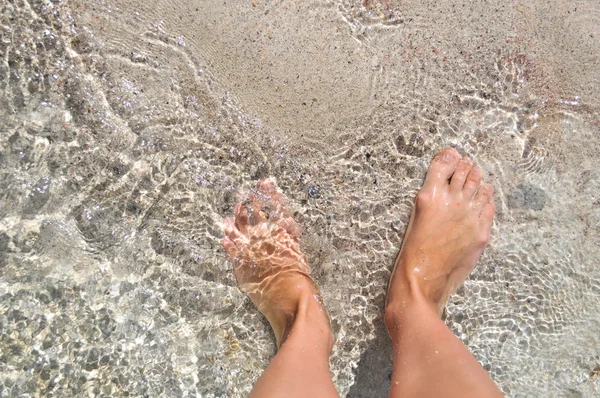 Feet in the water on the sand