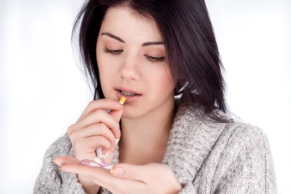 Girl holding a medicine and lozhet it in his mouth