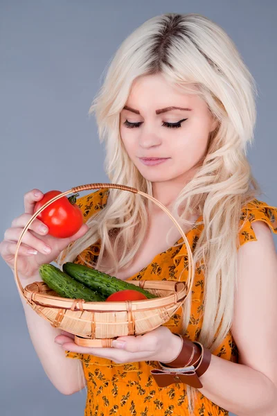 Blonde girl lays down a basket of tomatoes and looking down