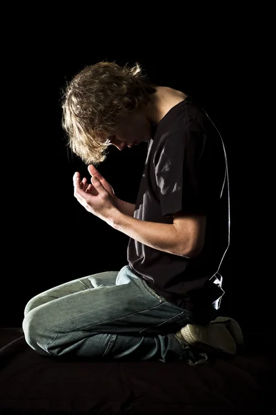 Young man kneels and prays