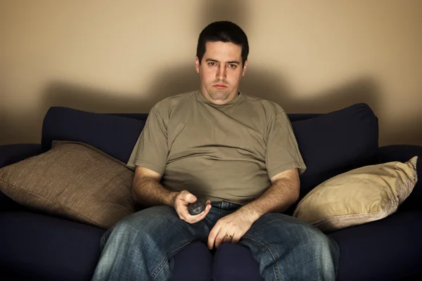 Bored, overweight man sits on the sofa