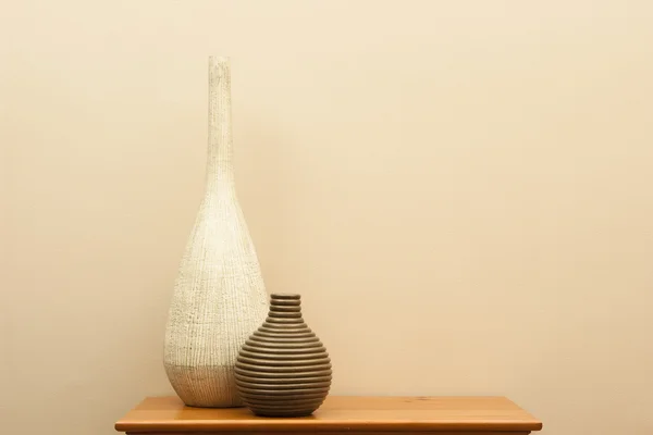 Tall white vase and short striped vase on small table