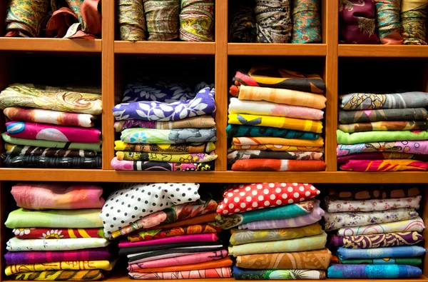 Multicolored scarfs on a shop counter, pile of colorful fabric