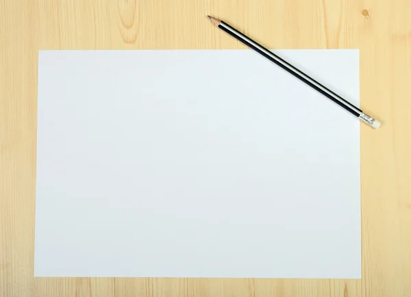 Blank page of paper and sharpened pencil on wooden floor