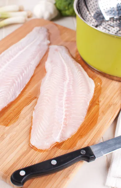 Raw fish fillets on cutting board