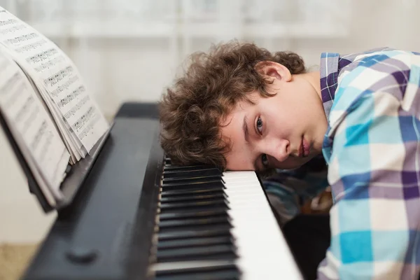 The boy has got tired to play the piano
