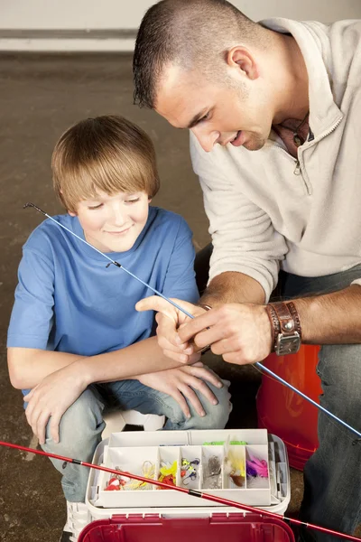 Young man helping adolescent boy with fishing equipment