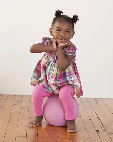 Headshot of toddler girl sitting on a ball