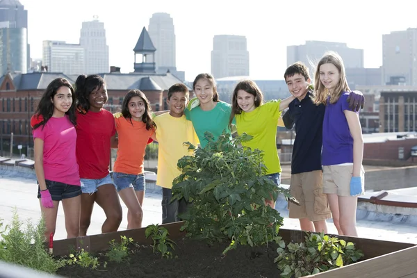 Children of different ethnicities standing proudly by the garden they planted