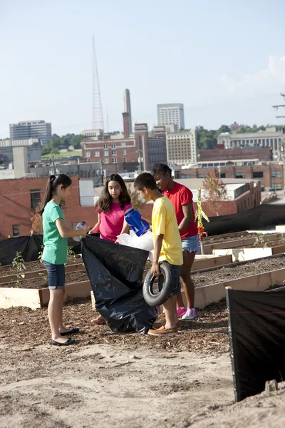 Group of children of different ethnicities picking up trash in an urban area