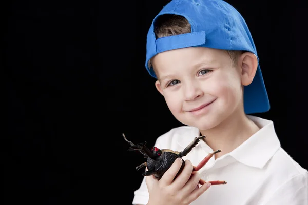 Little boy wearing his baseball cap and playing with toy bug