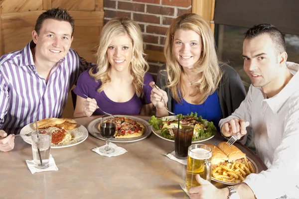 Caucasian adult couples eating together at a restaurant.
