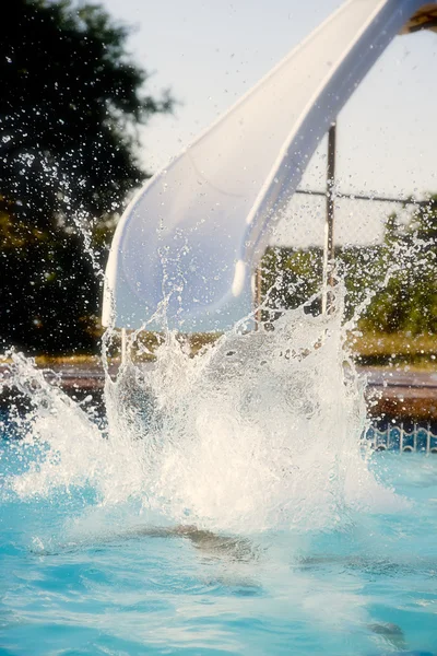 Summer Swimming. Child having fun in the summer sun by making a big splash on a water slide