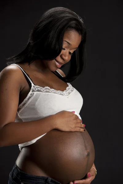 Real. Black expectant mother looking tenderly down at her abdomen