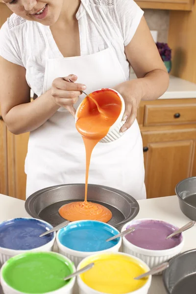 Rainbow Cake. Chef pouring batter into pans to make the colorful layers of a rainbow cake