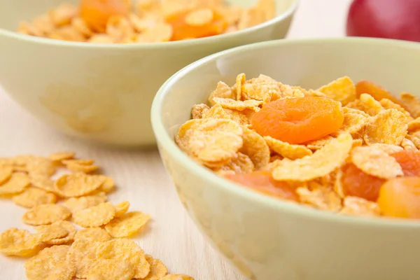 Green bowls of crunchy corn flakes for breakfast on wooden table