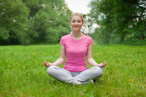 Blonde girl outdoor in the park wearing pink t-shirt. yoga