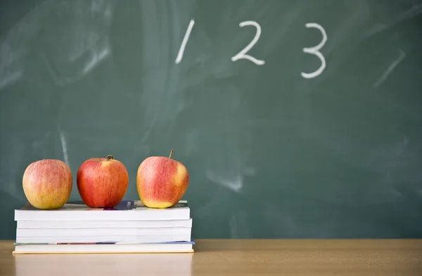 Books and apples with used green chalkboard in the background