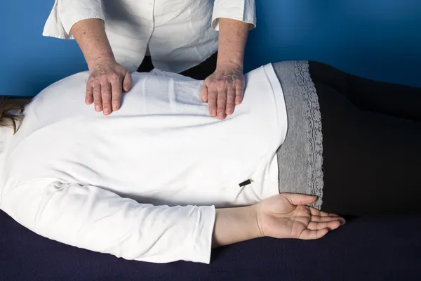 A young woman is getting a reiki treatment