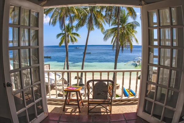 Room with a tropical beach view and balcony with bamboo furniture