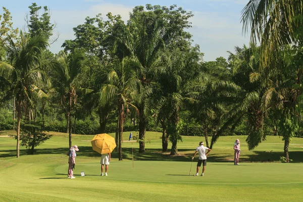 Golfers and caddies on golf course in Thailand