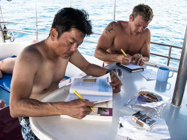 Scuba diving students studying onboard dive boat